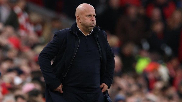 Potret Pelatih Liverpool, Arne Slot, mengenakan pakaian hitam di pinggir lapangan.