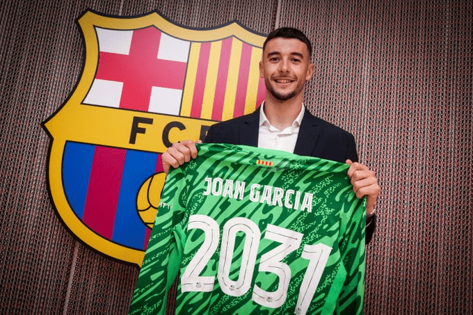 Joan Garcia berpose dengan jersey Barcelona bertuliskan kontrak hingga 2031 di depan logo klub
