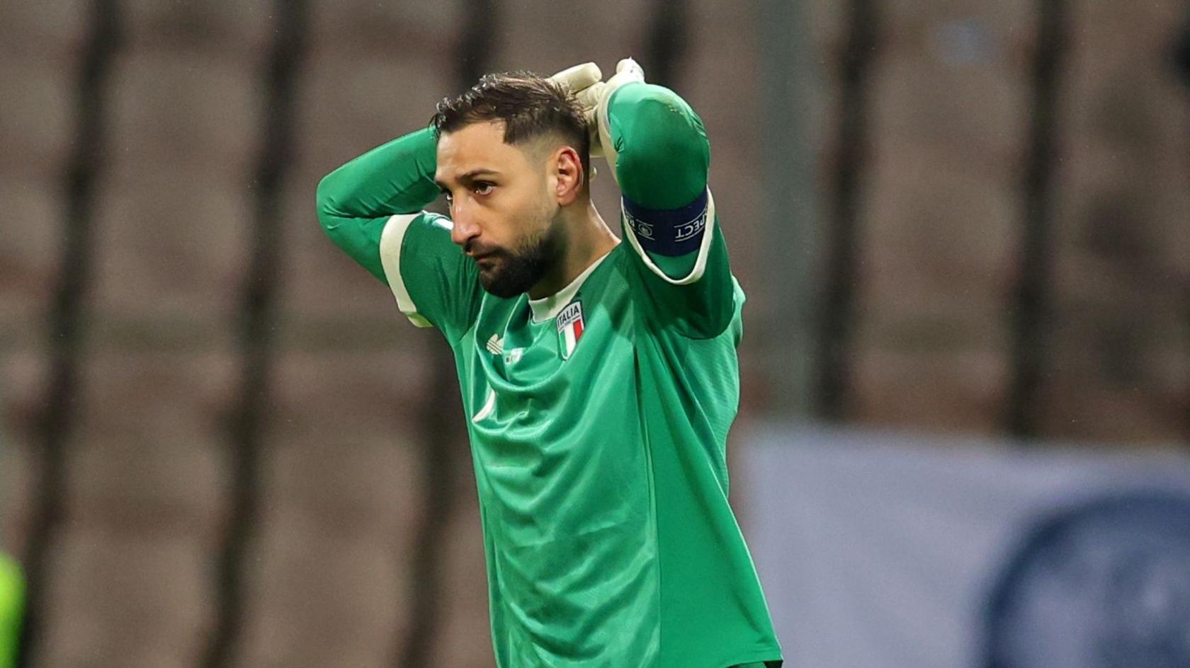 Kiper timnas Italia Gianluigi Donnarumma dengan seragam hijau, memegang kepala dengan kedua tangan menunjukkan ekspresi kecewa di lapangan.