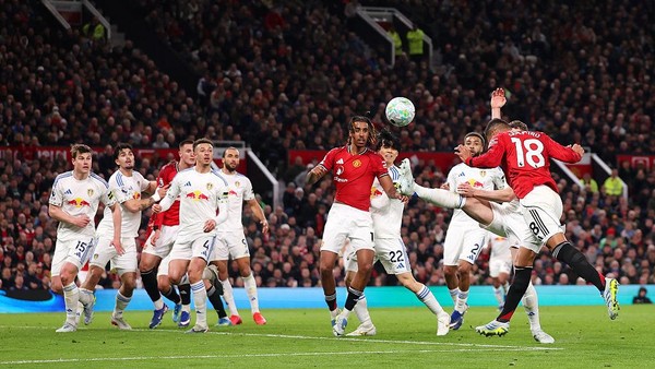 Pemain Manchester United dan Leeds United melakukan duel udara memperebutkan bola di dalam kotak penalti.
