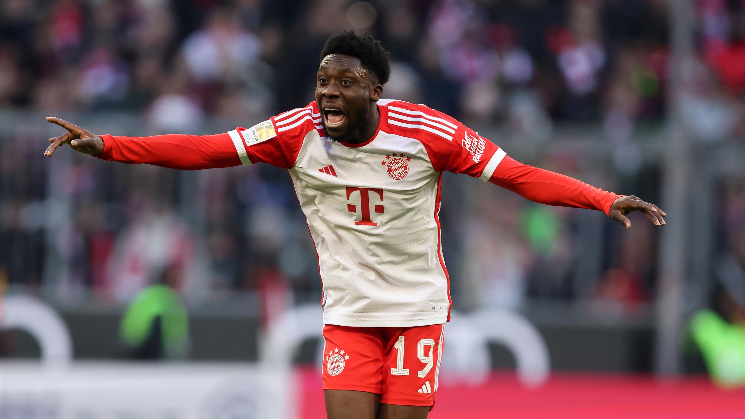 Selebrasi gol emosional Alphonso Davies dengan jersey Bayern Munchen, merentangkan tangan ke arah penonton. Rumor transfer Manchester United.