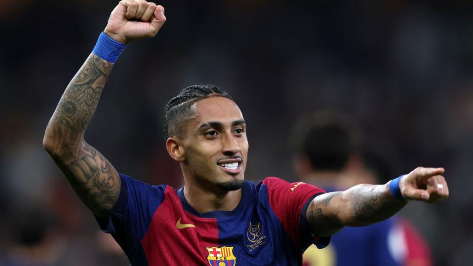 Pemain sayap Barcelona, Raphinha, mengepalkan tangan merayakan gol atau kemenangan di lapangan.