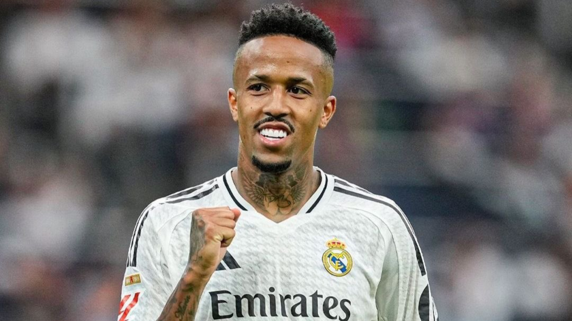 Eder Militao, bek Real Madrid, mengepalkan tangan merayakan momen di lapangan dengan latar belakang tribun penonton.