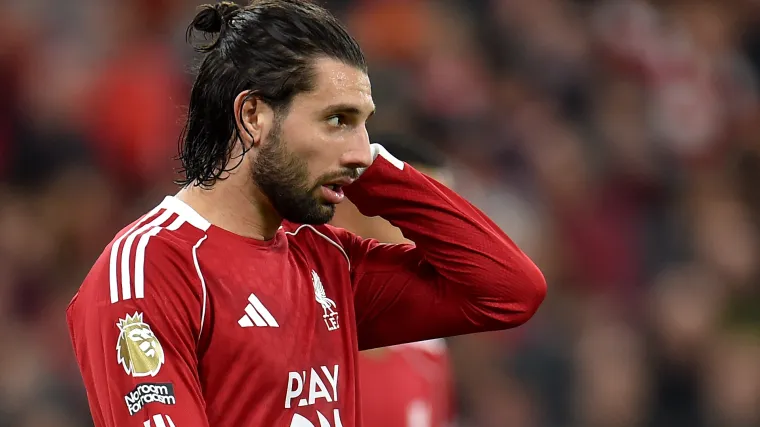 Seorang pemain sepak bola Liverpool berkostum merah terlihat tertunduk dengan ekspresi sedih dan memegang kepala, menggambarkan keputusasaan di stadion yang penuh