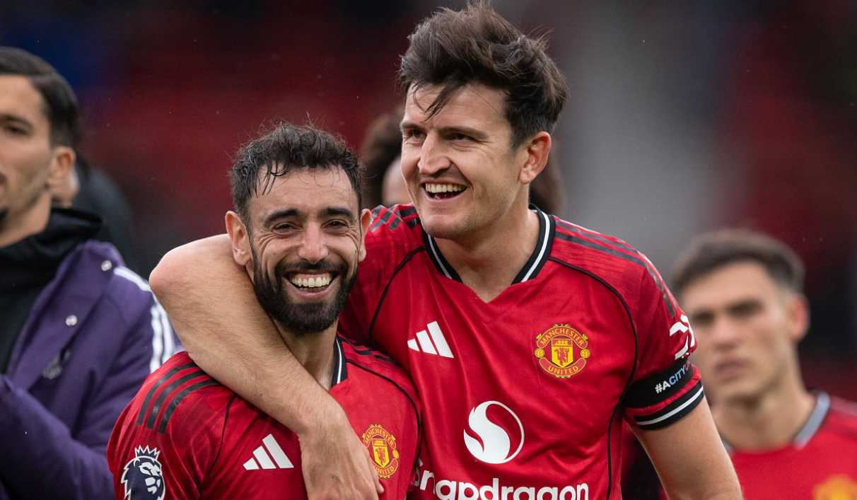 Harry Maguire memeluk Bruno Fernandes dengan latar belakang stadion setelah pertandingan Manchester United.