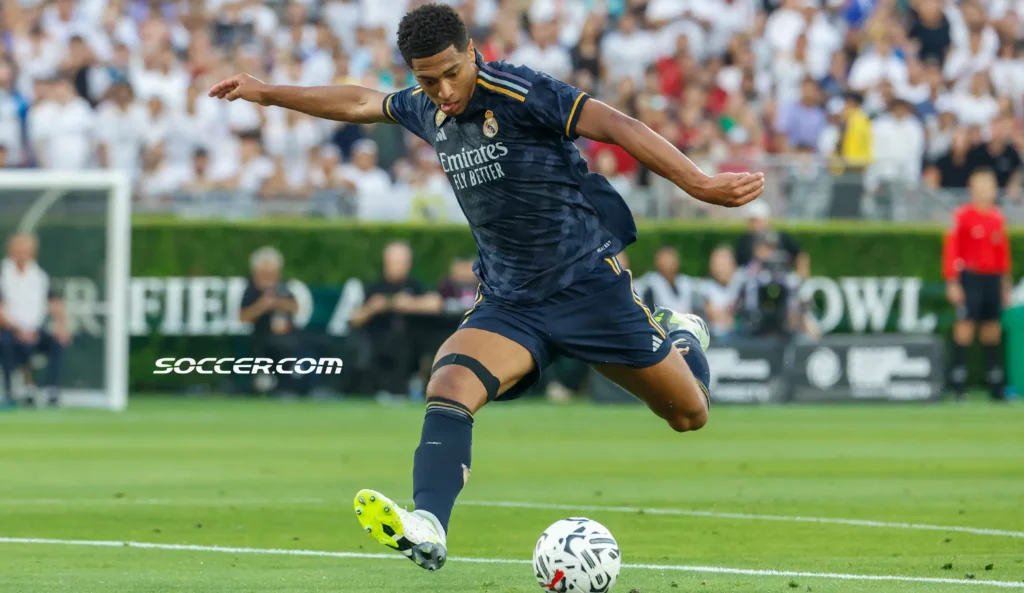 Jude Bellingham saat beraksi di lapangan mengenakan jersei Real Madrid, sedang menendang bola dalam sebuah pertandingan