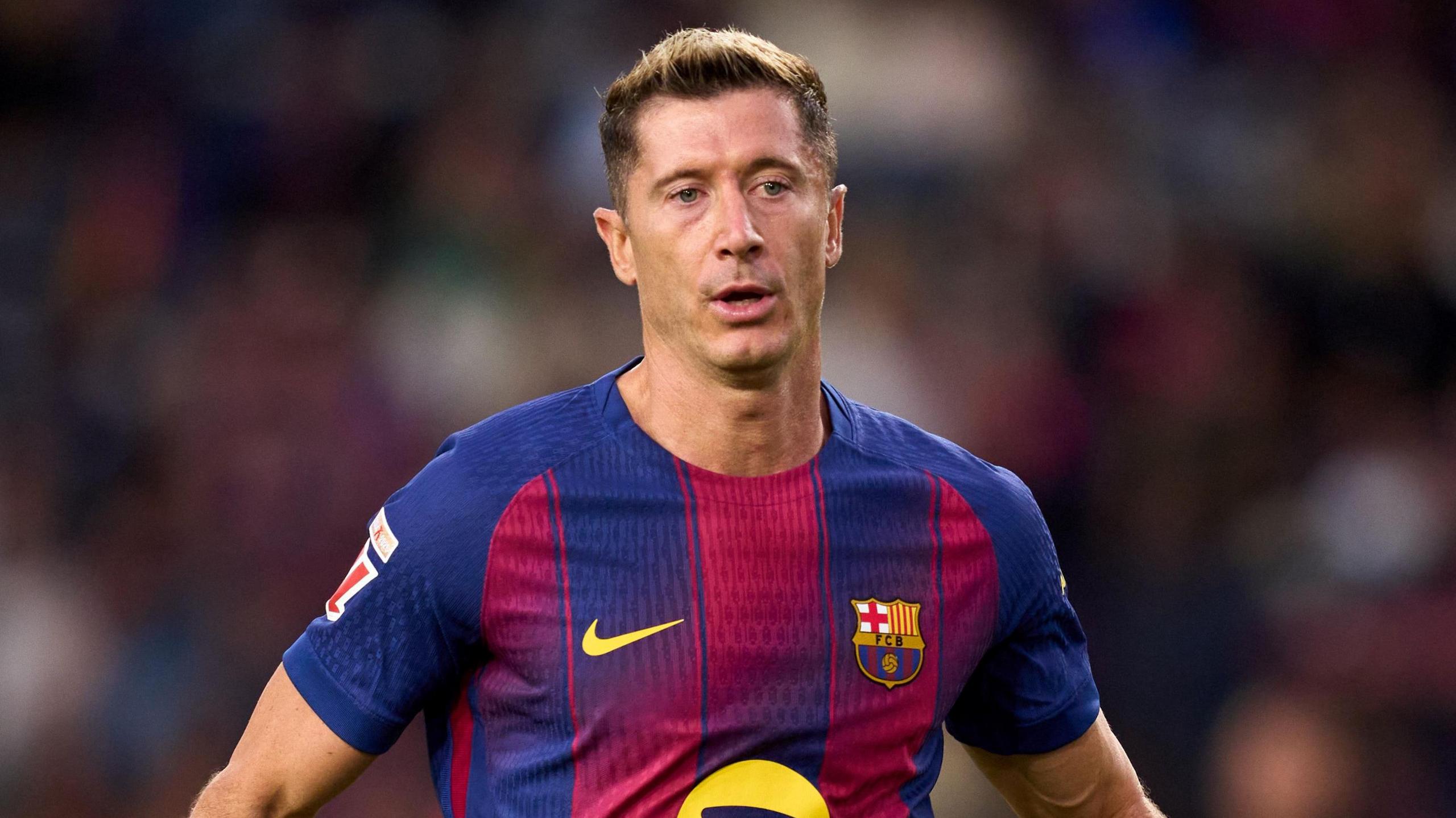 Robert Lewandowski mengenakan seragam Barcelona dalam pose merayakan gol atau memberikan instruksi di lapangan.