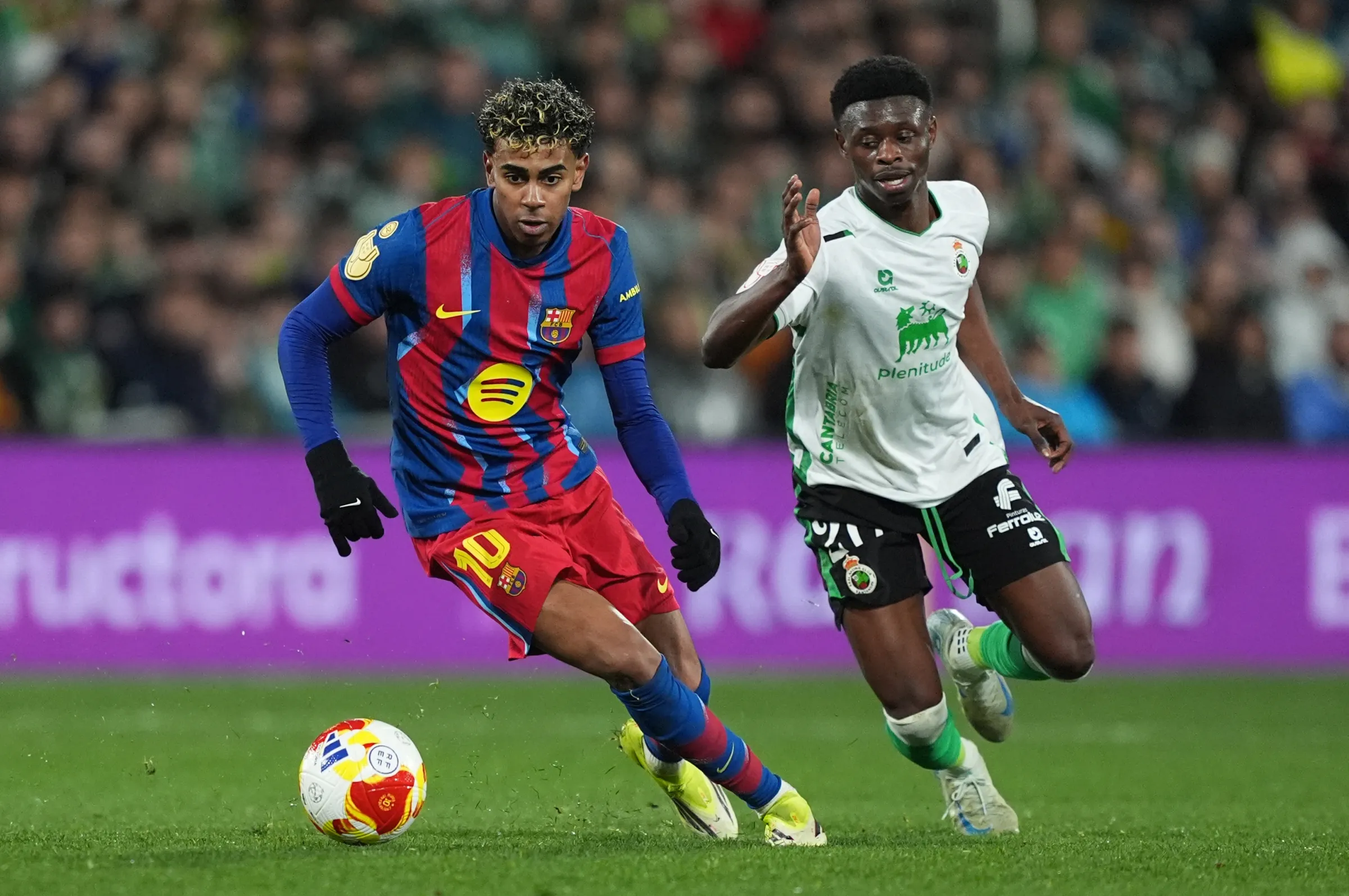 Lamine Yamal sedang menggiring bola melewati pemain bertahan Celta Vigo dalam pertandingan La Liga di Camp Nou.
