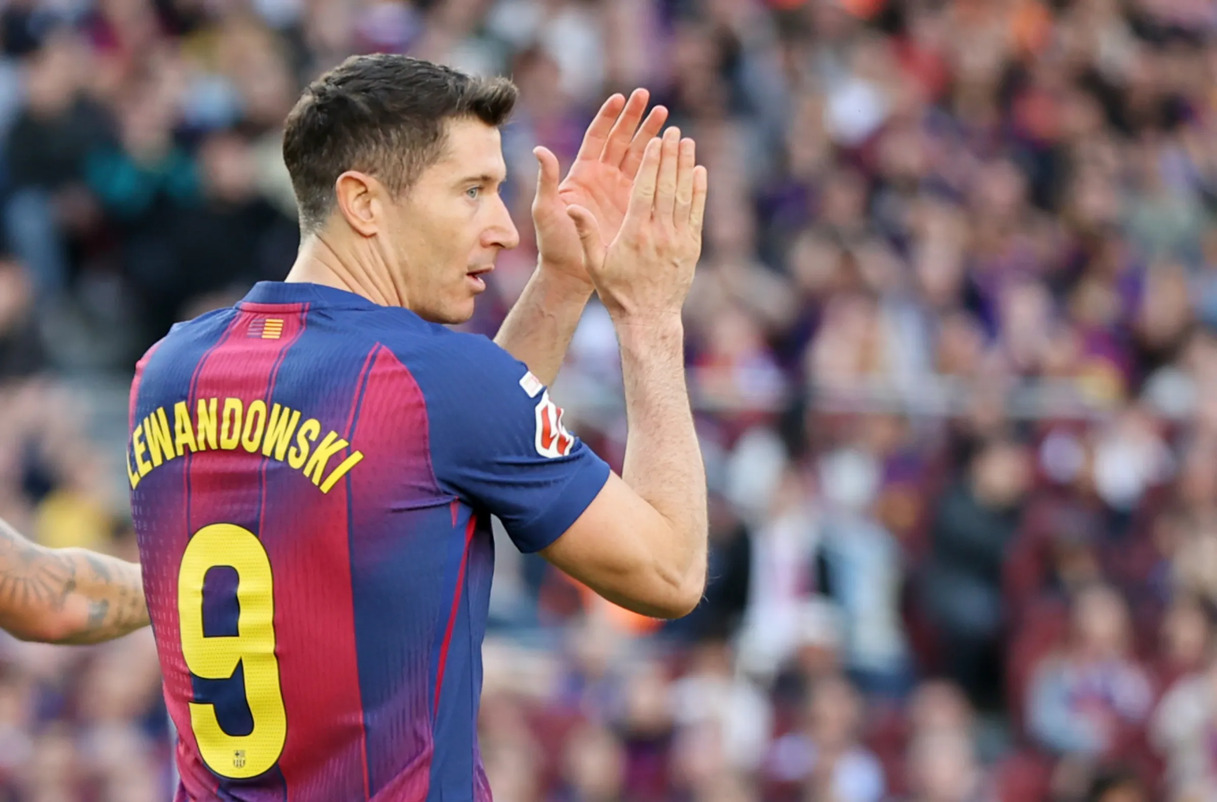 Robert Lewandowski tampak belakang mengenakan jersey Barcelona nomor 9, sedang bertepuk tangan ke arah tribun penonton.