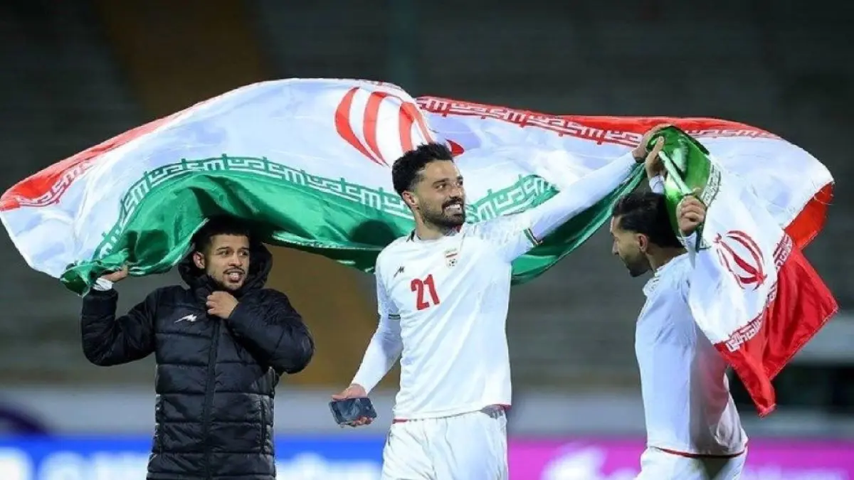 Pemain Tim Nasional Iran merayakan kemenangan dengan membentangkan bendera negara Iran di lapangan