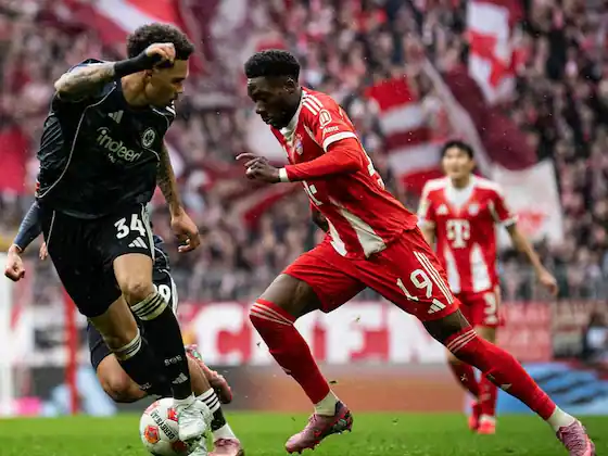 Aksi Alphonso Davies (jersey merah Bayern Munchen) saat menguasai bola dan menghindari tekel lawan di lapangan. Target transfer bek kiri Manchester United.