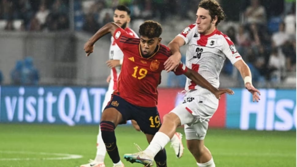 Lamine Yamal menggiring bola saat membela Timnas Spanyol dalam pertandingan internasional.