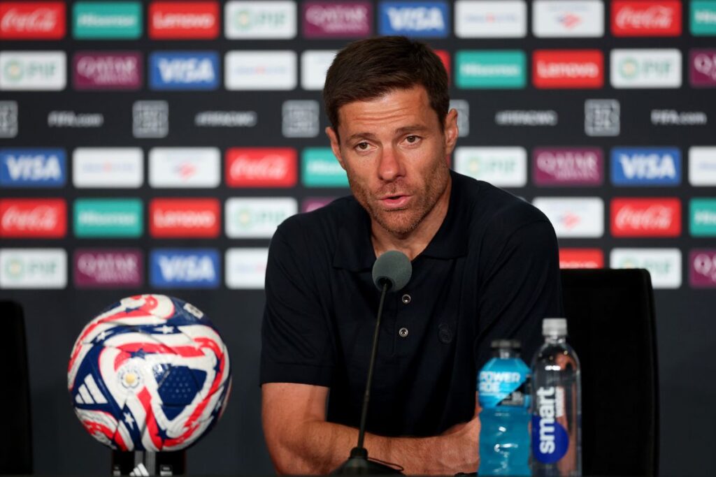 Xabi Alonso memberikan keterangan pers dengan latar belakang logo sponsor klub