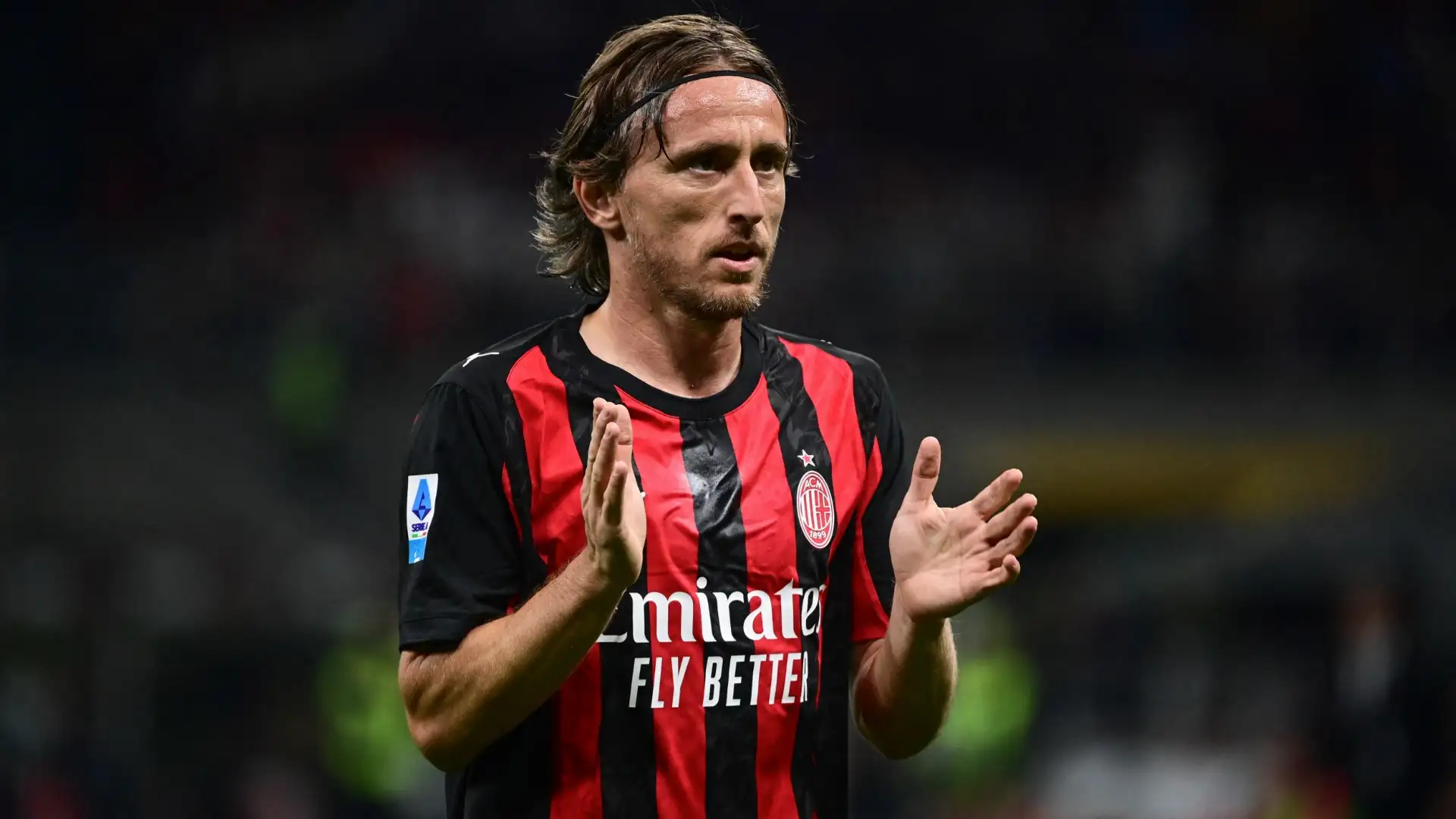 Luka Modric mengenakan jersey AC Milan bertepuk tangan di tengah lapangan saat pertandingan.