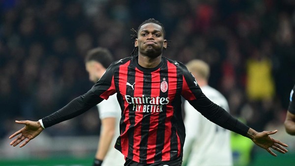 Rafael Leao mengenakan seragam AC Milan berdiri di lapangan dengan ekspresi serius atau kecewa