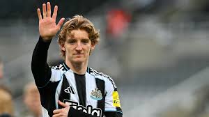 Anthony Gordon menggunakan jersi Newcastle United sambil melambaikan tangan.