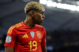 Lamine Yamal dengan jersei merah Timnas Spanyol nomor 19 di stadion.