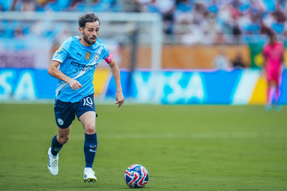 Bernardo Silva sedang menggiring bola sepak di tengah lapangan hijau dalam sebuah pertandingan.