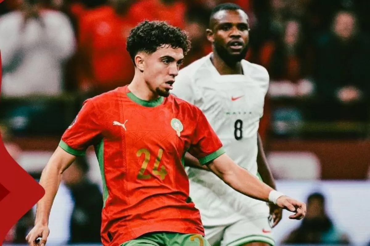 Pemain Timnas Maroko mengenakan jersei merah sedang menggiring bola dalam sebuah pertandingan sepak bola.