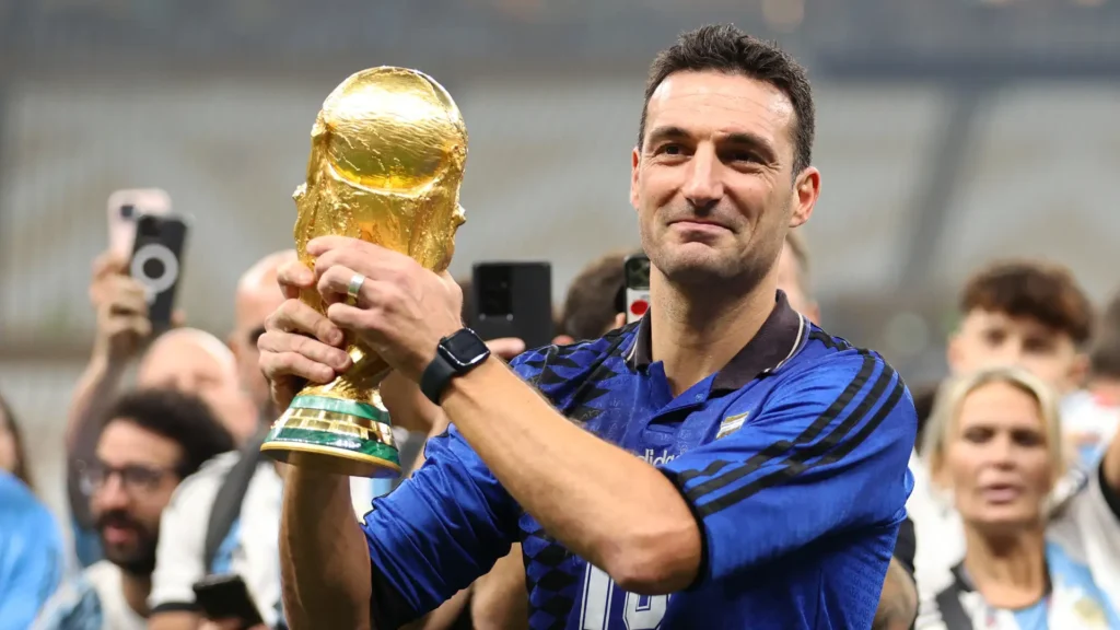 Pelatih Timnas Argentina Lionel Scaloni tersenyum sambil memegang trofi Piala Dunia.
