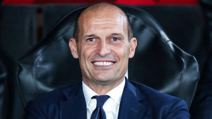 Massimiliano Allegri tersenyum di bangku cadangan stadion.