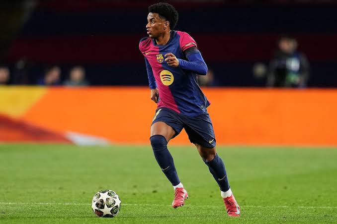 Alejandro Balde pemain Barcelona sedang menggiring bola di lapangan dengan seragam utama klub.