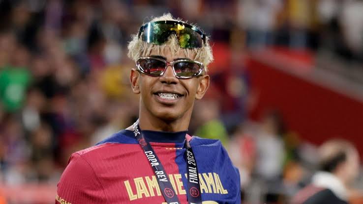 Pemain Timnas Spanyol Lamine Yamal tersenyum dengan kacamata di atas kepalanya saat berada di stadion.