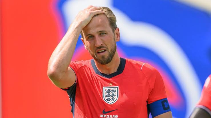 Kapten Timnas Inggris Harry Kane memegang kepala dengan ekspresi kecewa atau berpikir saat bertanding menggunakan jersei merah.