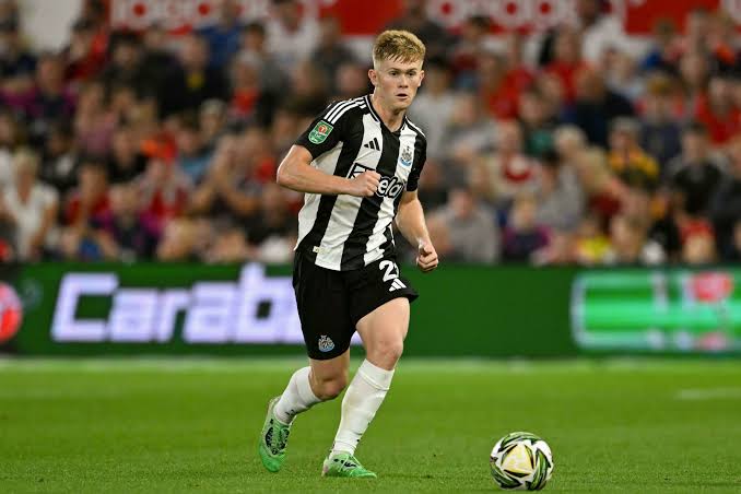 Lewis Hall saat bertanding untuk Newcastle United, dengan papan iklan Carabao di latar belakang