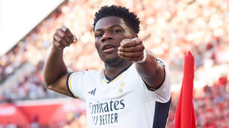 Aurelien Tchouameni mengepalkan tangan melakukan selebrasi di lapangan dengan mengenakan jersey putih Real Madrid.