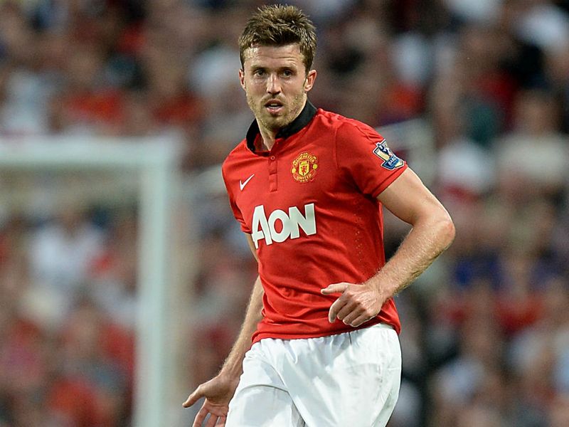 Michael Carrick saat aktif bermain mengenakan jersey merah ikonik Manchester United dengan sponsor Aon di lapangan.
