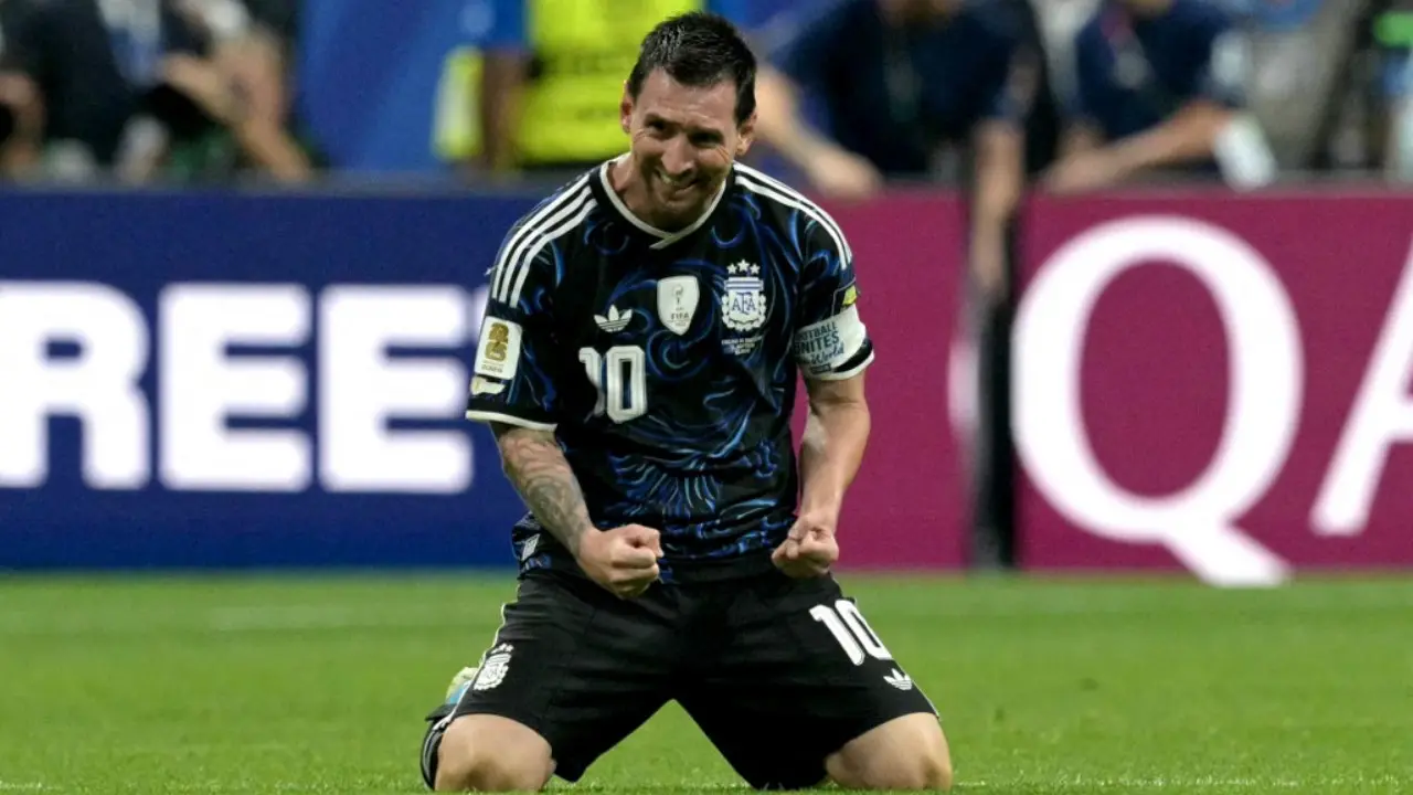 Lionel Messi mengenakan jersey timnas Argentina berwarna hitam strip putih sedang mengepalkan kedua tangan merayakan gol atau kemenangan di lapangan sepak bola.