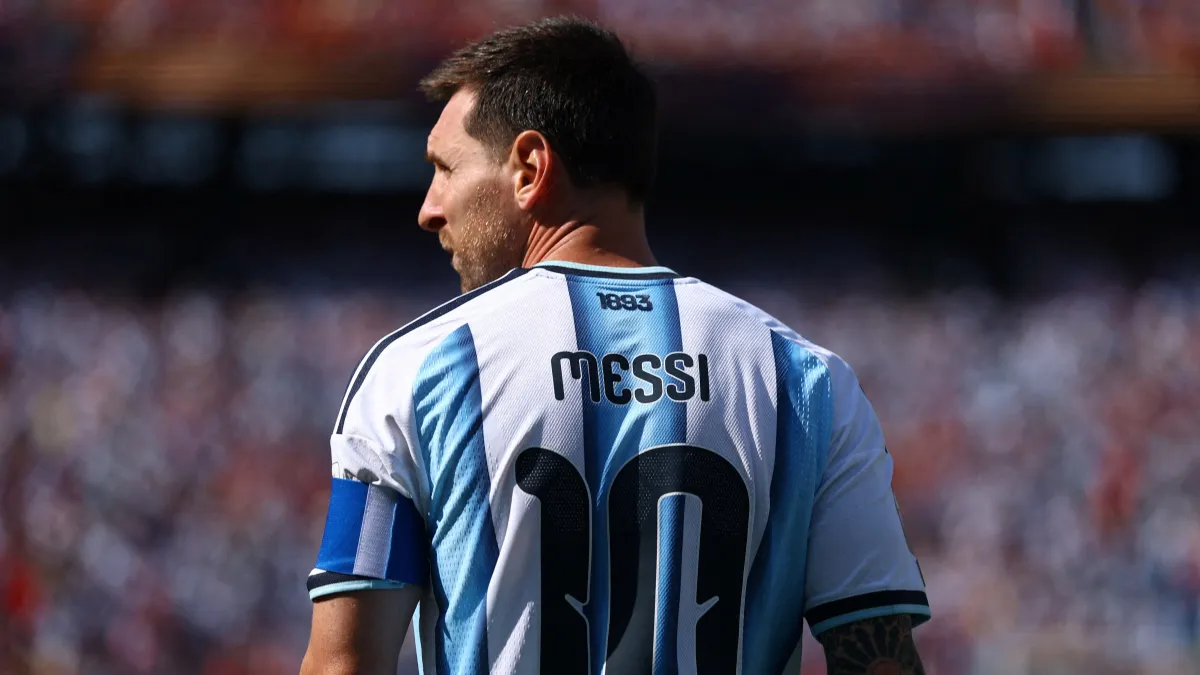 Lionel Messi tampak dari belakang dengan jersey Argentina nomor 10 di lapangan hijau, tampak lesu