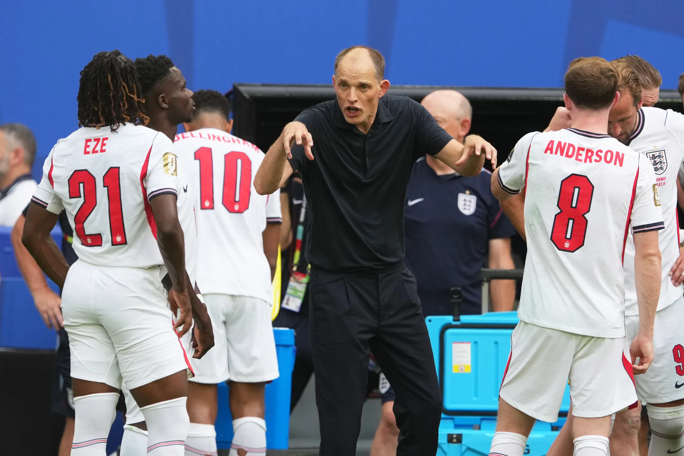 Pelatih Timnas Inggris Thomas Tuchel sedang memberikan instruksi taktis dengan ekspresi intens kepada para pemainnya di pinggir lapangan.
