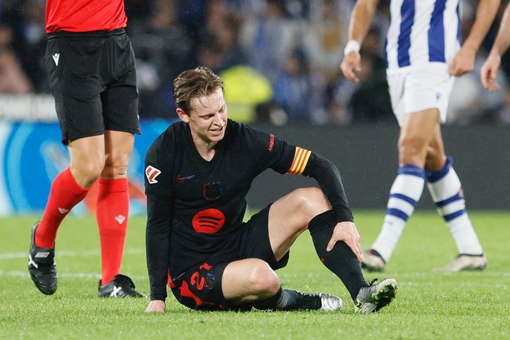 Frenkie de Jong terduduk memegang kaki kanan akibat cedera saat bertanding.