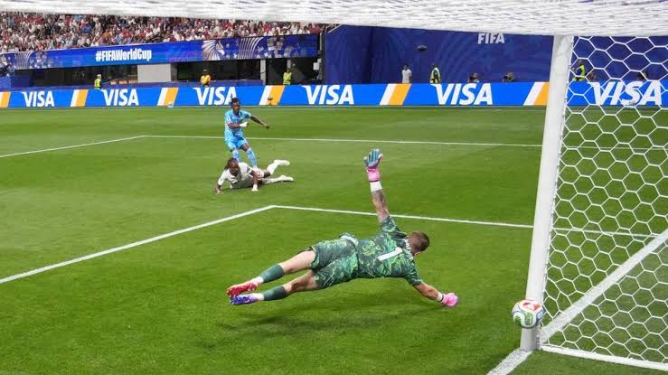 Kiper meloncat mencoba menyelamatkan bola yang masuk ke arah pojok gawang dalam pertandingan sepak bola.