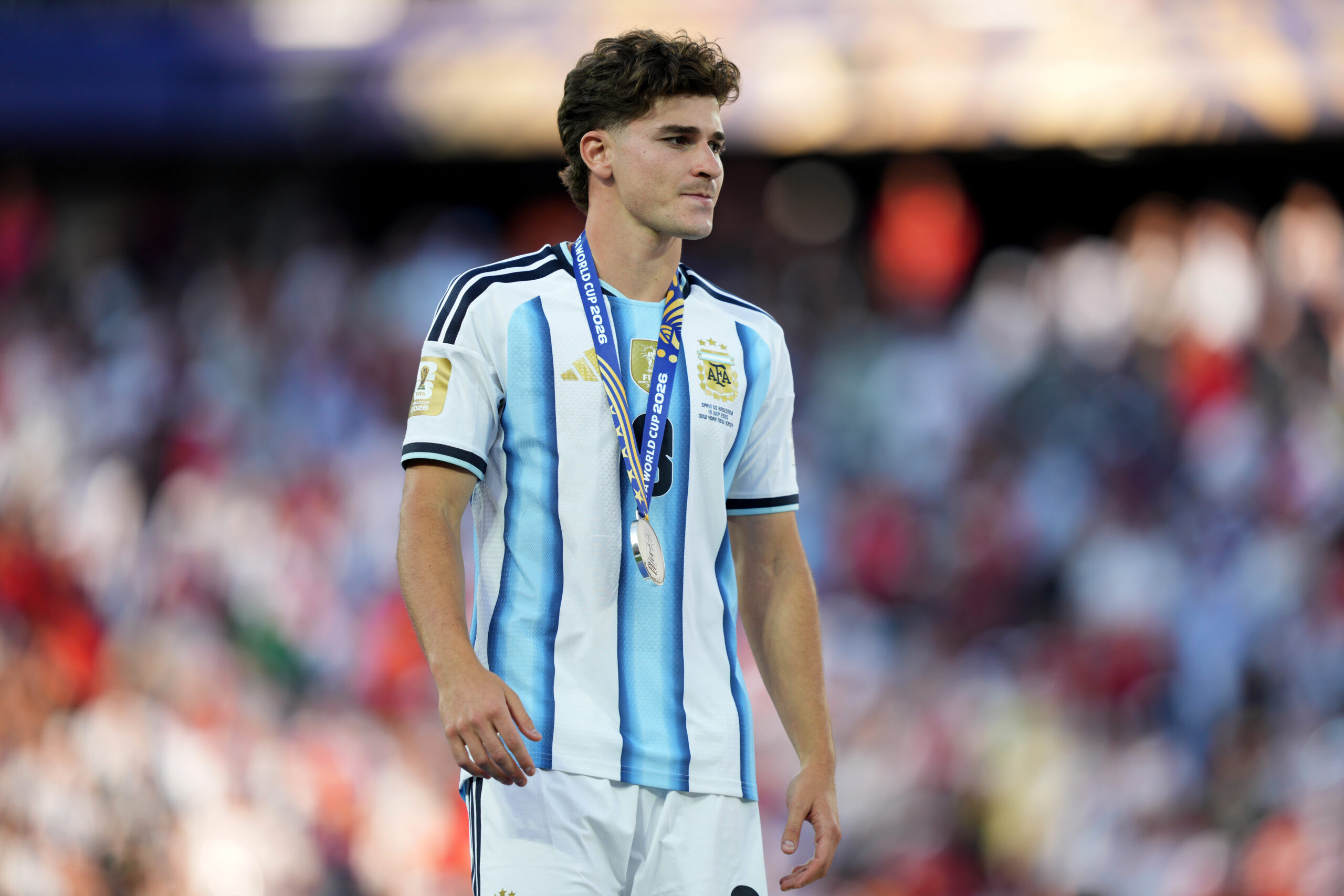 Julian Alvarez mengenakan jersey tim nasional Argentina dengan medali di lehernya.
