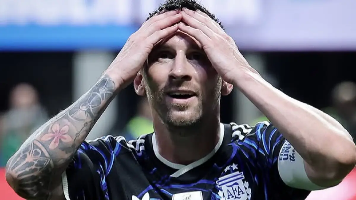 Kapten Argentina Lionel Messi memegang kepala dengan ekspresi serius di lapangan sepak bola.