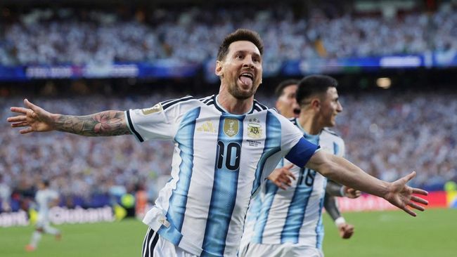 Lionel Messi dengan jersei garis biru-putih khas Argentina merentangkan kedua tangannya saat merayakan gol di lapangan sepak bola.