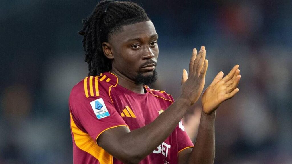 Manu Kone bertepuk tangan mengenakan jersey AS Roma.