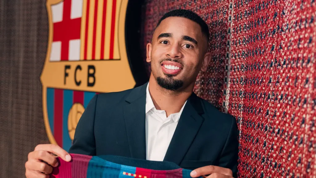 Gabriel Jesus tersenyum sambil memegang jersey Barcelona