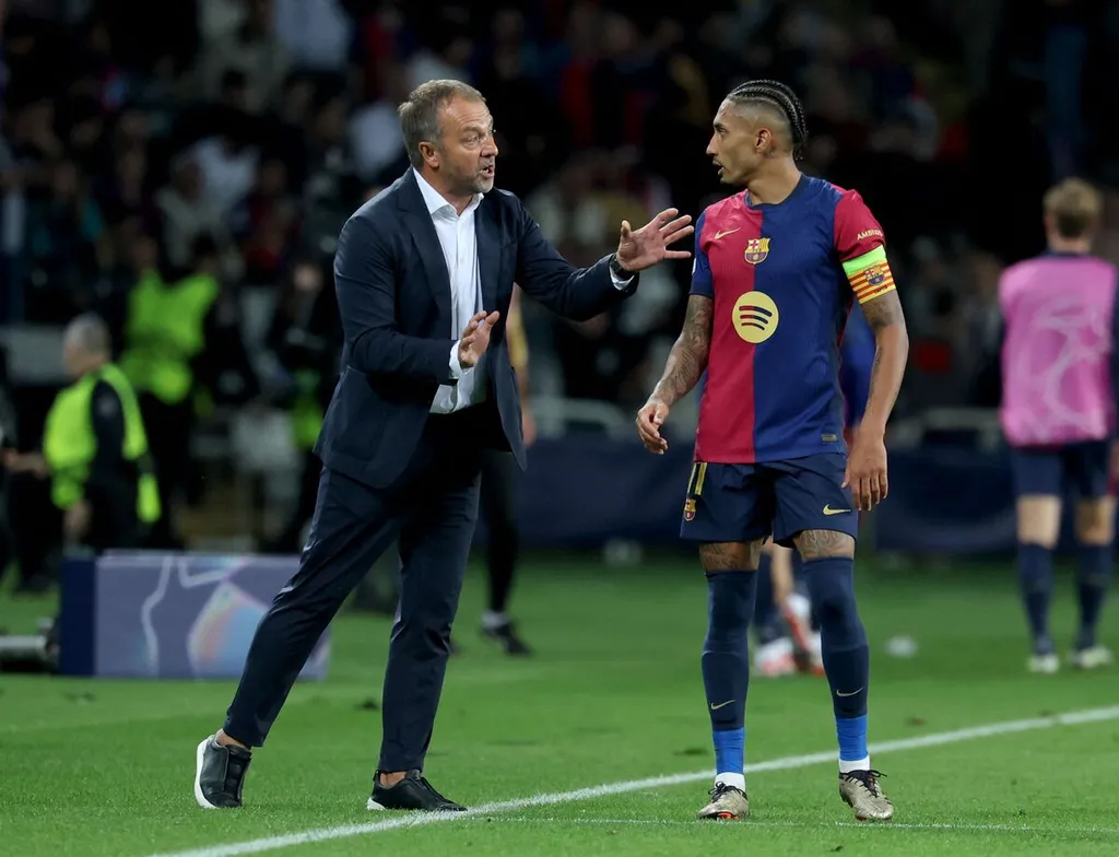 Hansi Flick memberikan instruksi taktis kepada Raphinha di pinggir lapangan saat pertandingan Barcelona.
