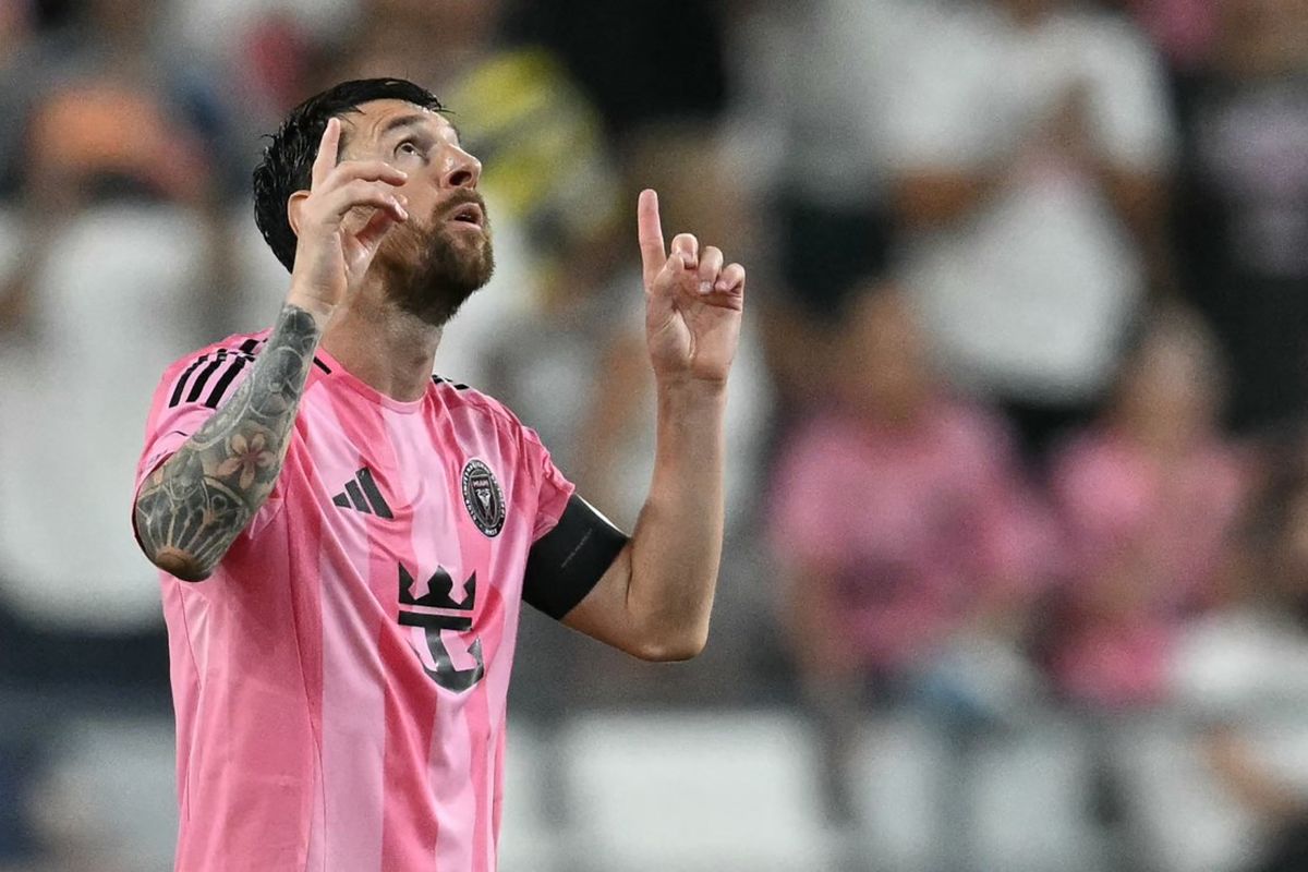 Lionel Messi tersenyum dan merayakan gol dengan menunjuk ke langit.