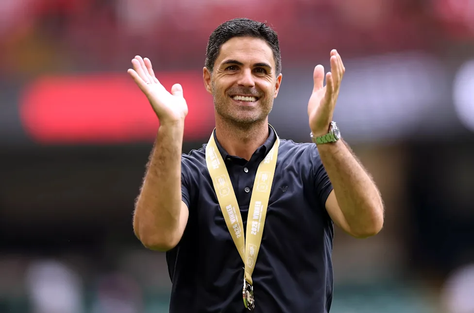 Mikel Arteta memberikan tepuk tangan dengan medali juara di lehernya.