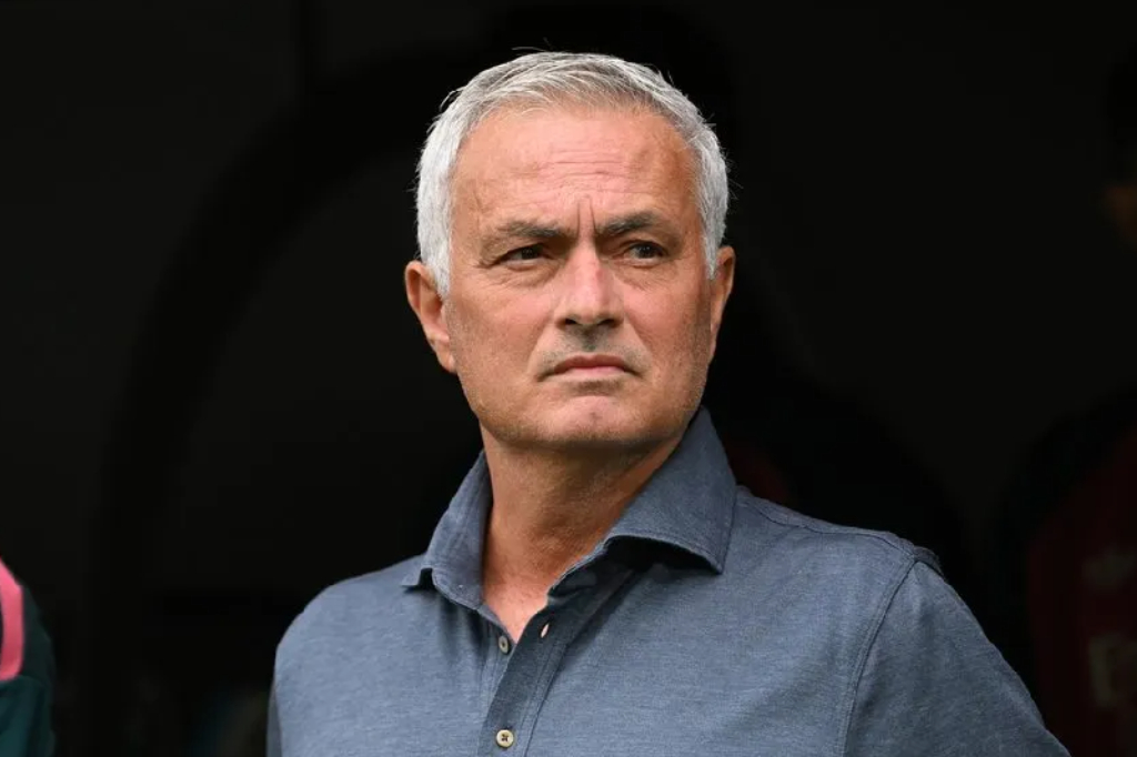 Jose Mourinho mengenakan kemeja biru berdiri di pinggir lapangan.
